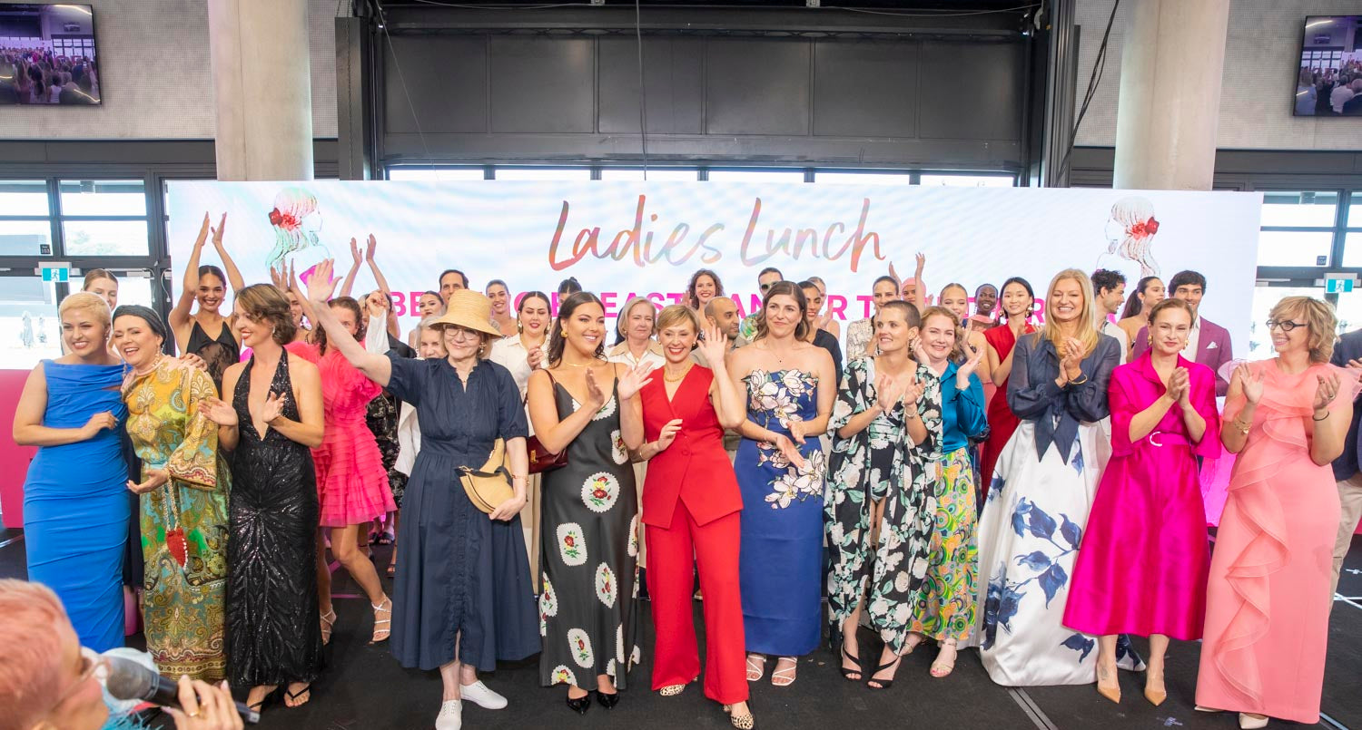 Group of women posing for a photo at an event with a 'Ladies Lunch' banner in the background.